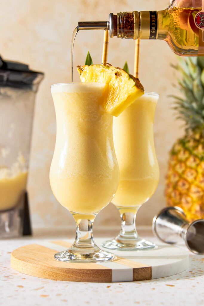 Piña Colada cocktail in hurricane glass with pineapple garnish