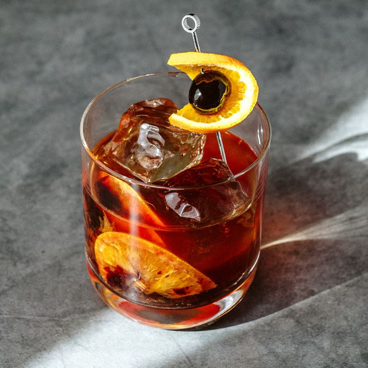 Old Fashioned cocktail with orange peel and ice cube