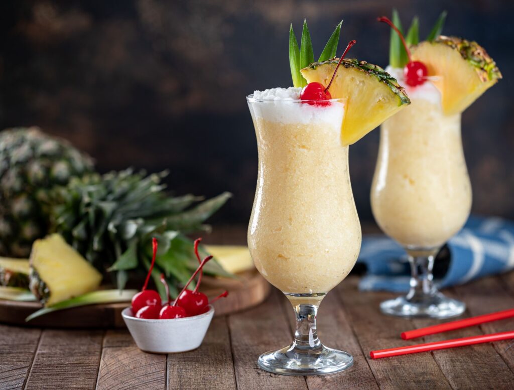 Piña Colada cocktail in hurricane glass with pineapple garnish